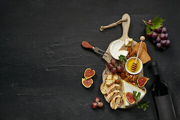 Image showing Two glasses of red wine and cheese plate with fruit on the black stone