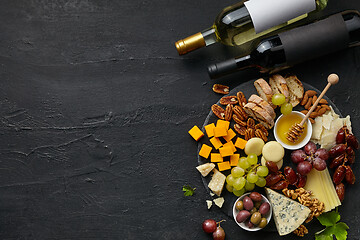 Image showing Top view of tasty cheese plate with fruit on the black stone