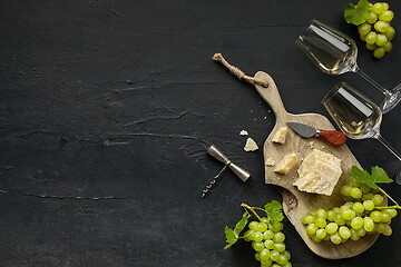Image showing Two glasses of white wine and a tasty cheese plate on a wooden kitchen plate.