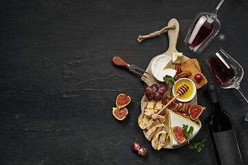 Image showing Two glasses of red wine and cheese plate with fruit on the black stone