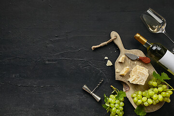 Image showing Two glasses of white wine and a tasty cheese plate on a wooden kitchen plate.