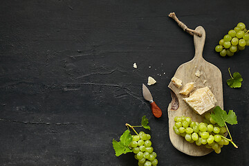 Image showing Top view of tasty cheese plate with the fruit on the black stone