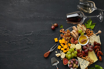 Image showing Top view of tasty cheese plate with fruit on the black stone