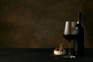 Image showing Front view of tasty fruit plate with the wine bottle on dark studio background