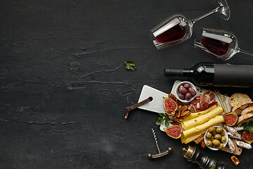 Image showing Two glasses of red wine and cheese plate with fruit on the black stone