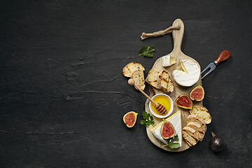 Image showing Two glasses of red wine and cheese plate with fruit on the black stone