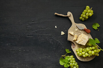 Image showing Top view of tasty cheese plate with the fruit on the black stone