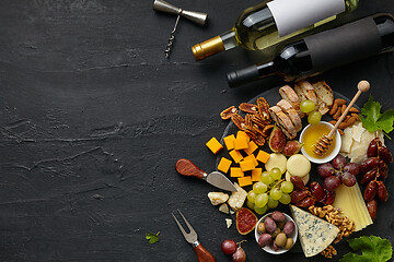 Image showing Top view of tasty cheese plate with fruit on the black stone