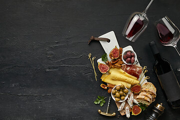 Image showing Two glasses of red wine and cheese plate with fruit on the black stone