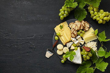 Image showing Top view of tasty cheese plate with fruit on the black stone