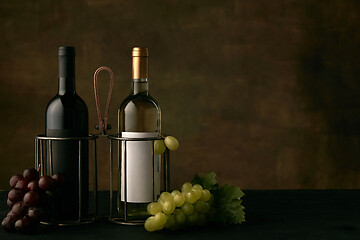 Image showing Front view of tasty fruit plate with the wine bottles on dark studio background