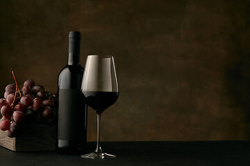 Image showing Front view of tasty fruit plate with the wine bottle on dark studio background