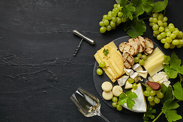 Image showing Top view of tasty cheese plate with fruit on the black stone