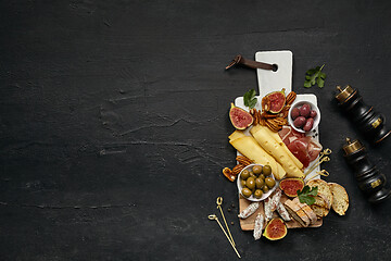 Image showing Top view of tasty cheese plate with the fruit on the black stone