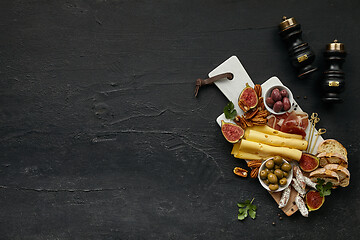 Image showing Top view of tasty cheese plate with the fruit on the black stone