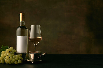 Image showing Front view of tasty fruit plate with the wine bottle on dark studio background