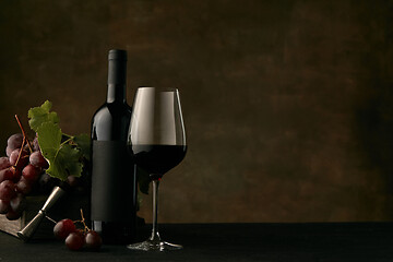 Image showing Front view of tasty fruit plate with the wine bottle on dark studio background