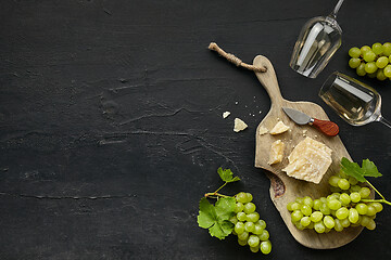 Image showing Two glasses of white wine and a tasty cheese plate on a wooden kitchen plate.