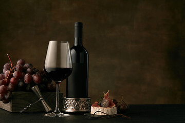 Image showing Front view of tasty fruit plate with the wine bottle on dark studio background