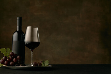 Image showing Front view of tasty fruit plate with the wine bottle on dark studio background