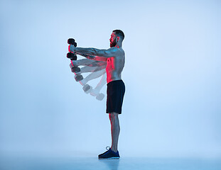 Image showing Young caucasian bodybuilder training over blue background