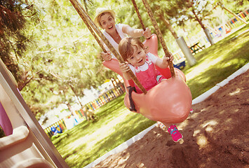 Image showing mother and daughter swinging in the park