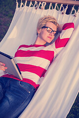 Image showing woman using a tablet computer while relaxing on hammock