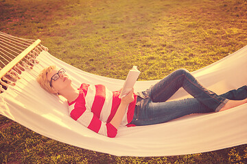 Image showing woman reading a book while relaxing on hammock