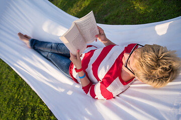 Image showing woman reading a book while relaxing on hammock