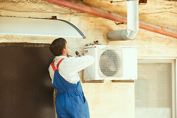 Image showing HVAC technician working on a capacitor part for condensing unit