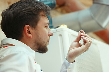 Image showing HVAC technician working on a capacitor part for condensing unit