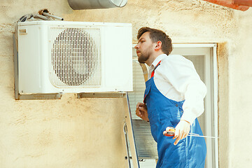 Image showing HVAC technician working on a capacitor part for condensing unit