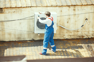 Image showing HVAC technician working on a capacitor part for condensing unit