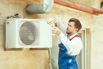 Image showing HVAC technician working on a capacitor part for condensing unit