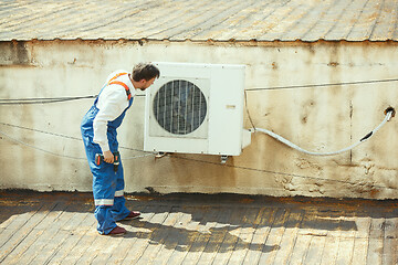 Image showing HVAC technician working on a capacitor part for condensing unit