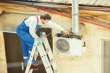 Image showing HVAC technician working on a capacitor part for condensing unit