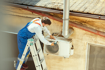 Image showing HVAC technician working on a capacitor part for condensing unit