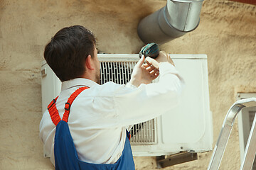 Image showing HVAC technician working on a capacitor part for condensing unit