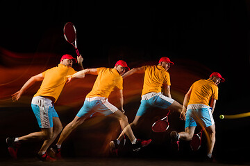 Image showing One caucasian man playing tennis on black background