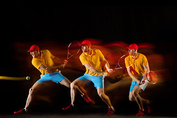 Image showing One caucasian man playing tennis on black background