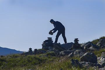 Image showing Man silhouette building a stone pile mark