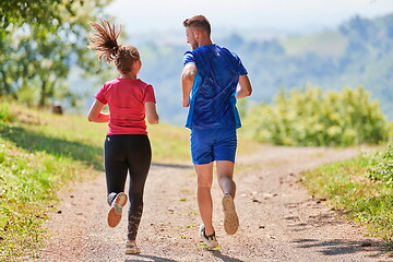 Image showing couple enjoying in a healthy lifestyle while jogging on a country road