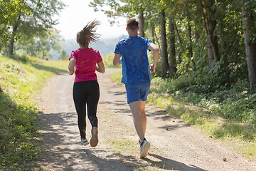 Image showing couple enjoying in a healthy lifestyle while jogging on a country road