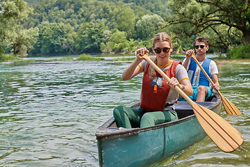 Image showing friends are canoeing in a wild river