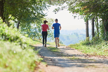 Image showing couple enjoying in a healthy lifestyle while jogging on a country road