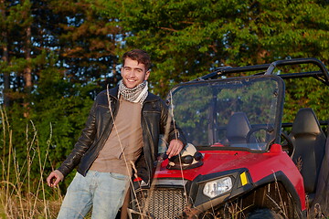 Image showing man smoking a cigarette while taking a break from driving a off road buggy car
