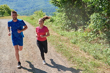 Image showing couple enjoying in a healthy lifestyle while jogging on a country road