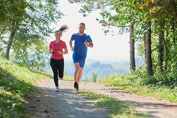 Image showing couple enjoying in a healthy lifestyle while jogging on a country road