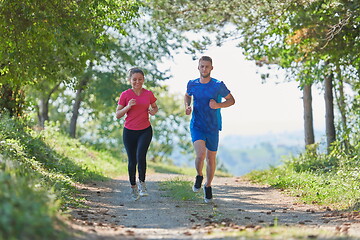 Image showing couple enjoying in a healthy lifestyle while jogging on a country road