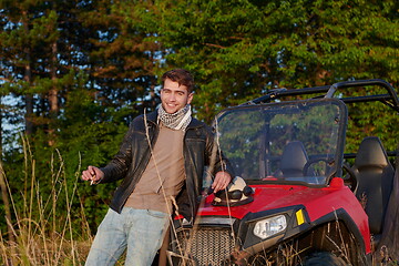 Image showing man smoking a cigarette while taking a break from driving a off road buggy car